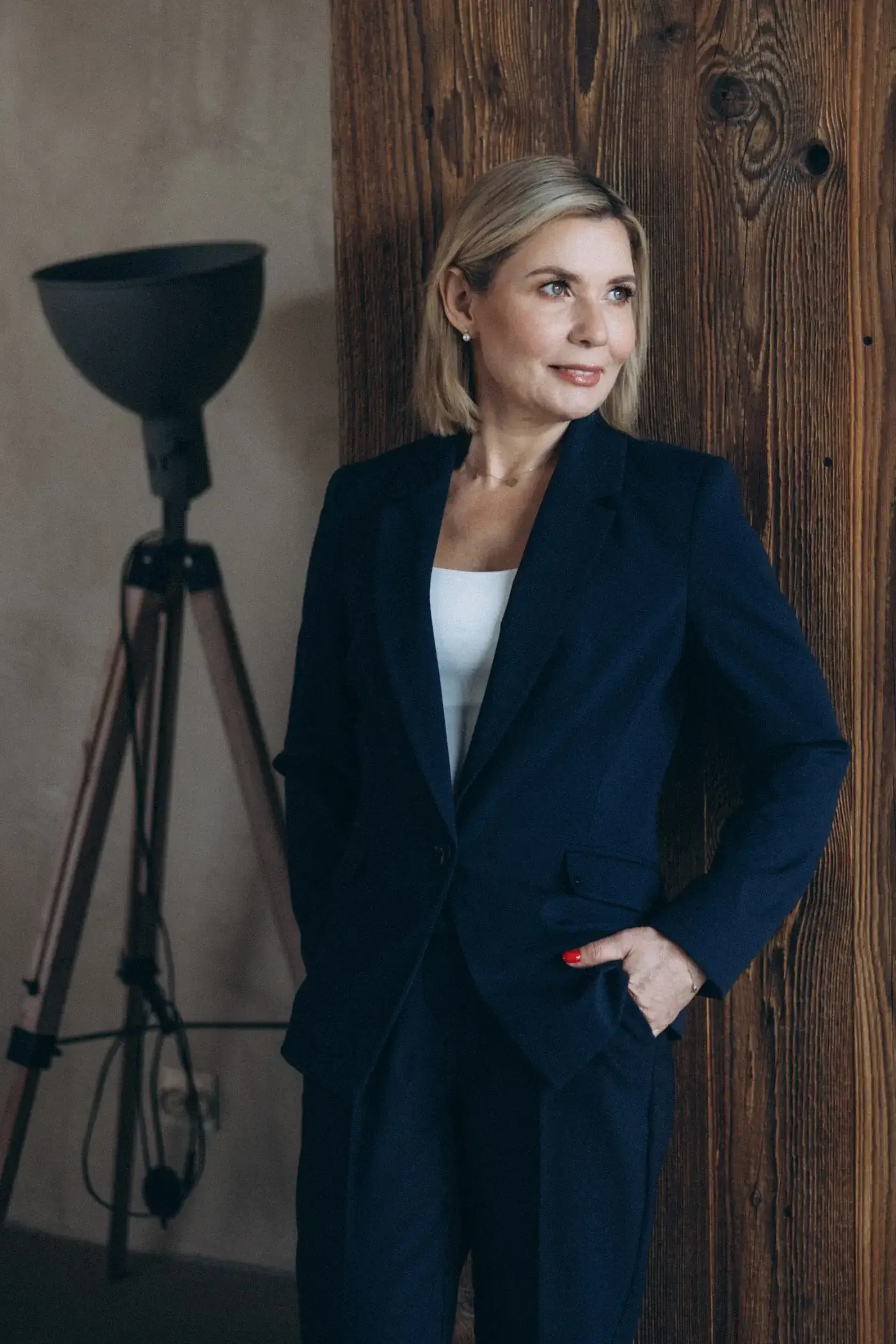 Portret Ewy Pędzich-Ościłowskiej w&nbsp;granatowym garniturze przy drewnianej ścianie ilustruje audyt ubezpieczeniowy.