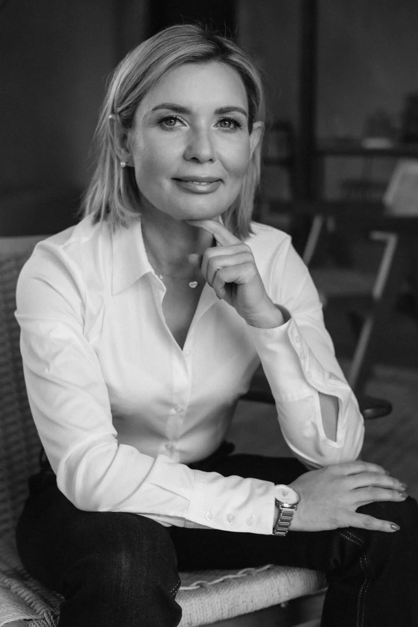 Sukcesja właściciela Czarno-biały portret Ewy Pędzich-Ościłowskiej w białej koszuli, siedzącej w fotelu.
